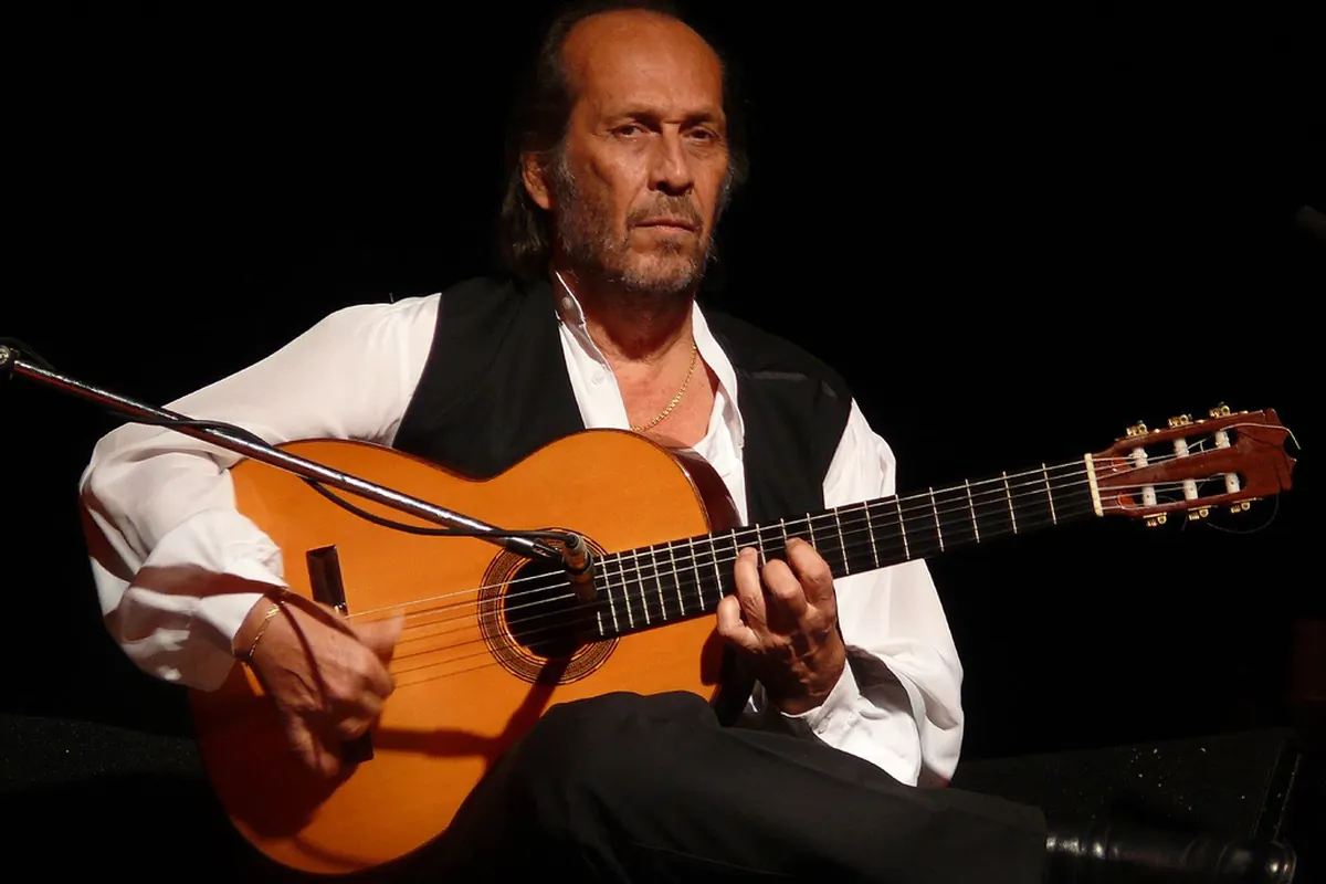 Paco de Lucía mit einer Flamencogitarre auf der Bühne sitzend